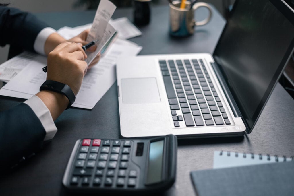 Business owner checking a receipt beside a laptop and calculator