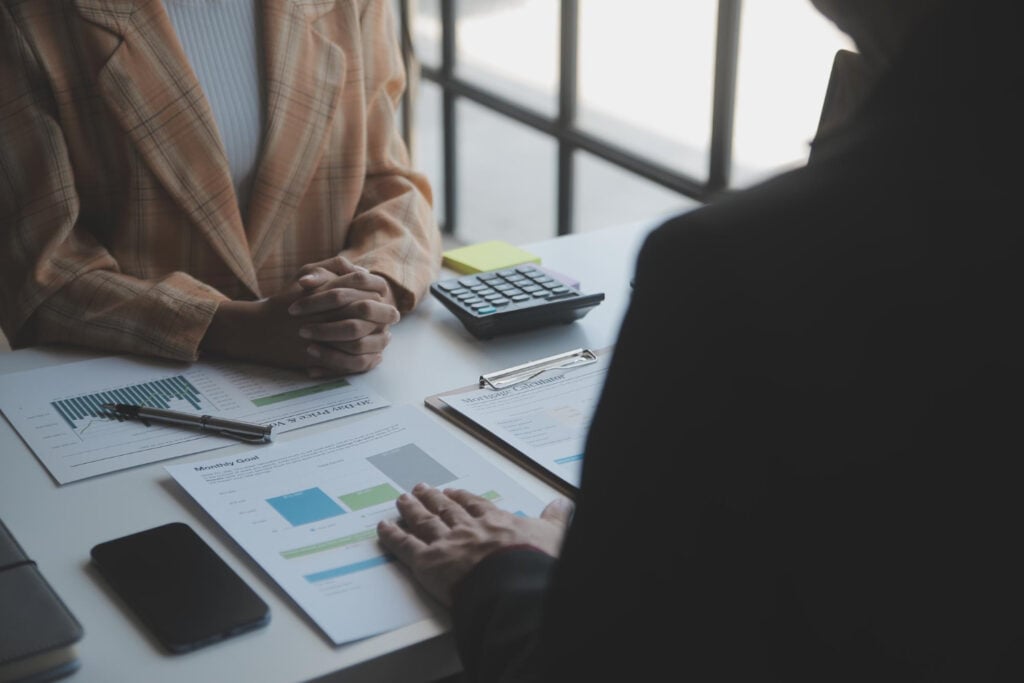 Two people reviewing financial charts beside a calculator