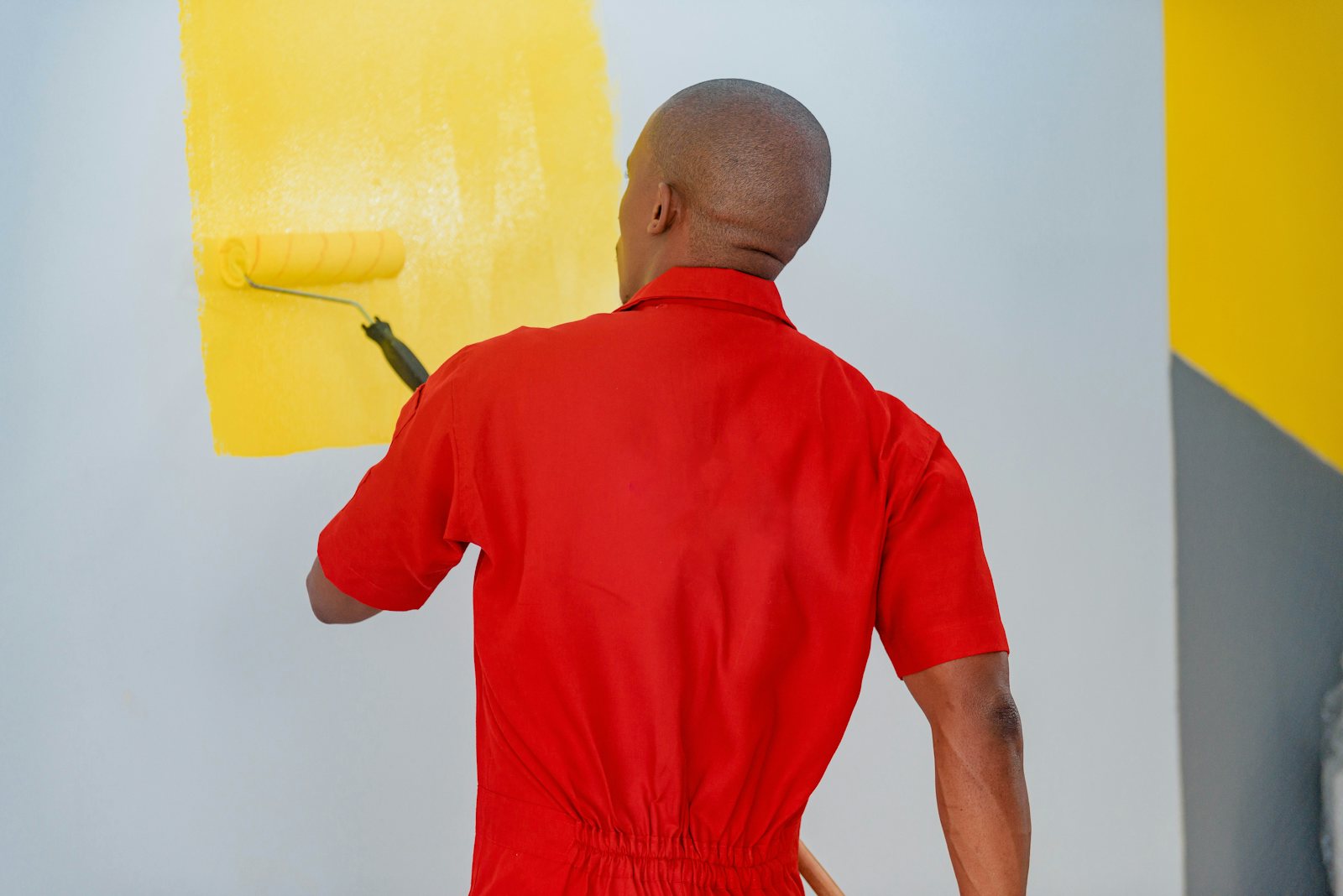 Painter rolling yellow paint onto an interior wall