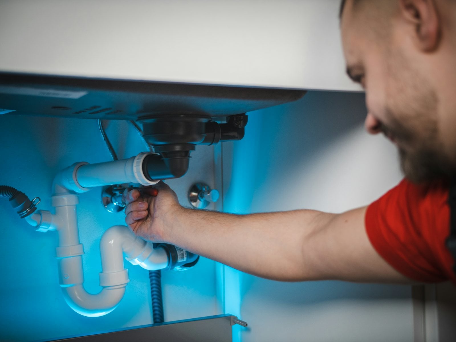 Plumber repairing the drain pipe under a sink