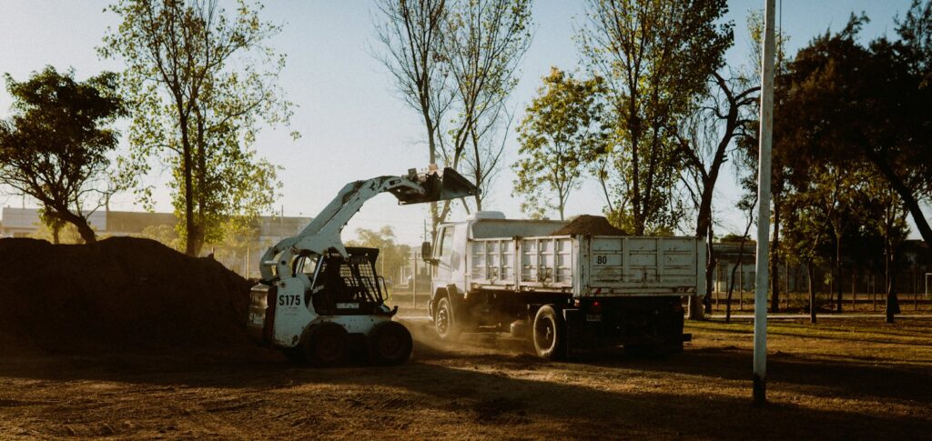 Skid steer loading dirt into a dump truck on a job site