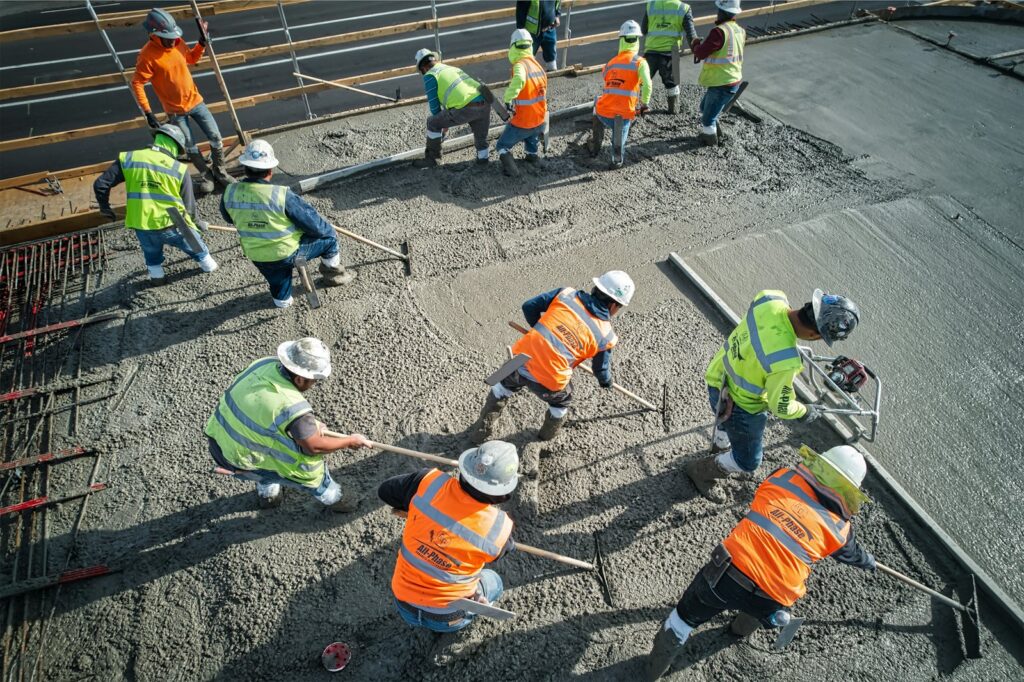 Crew in safety vests spreading wet concrete