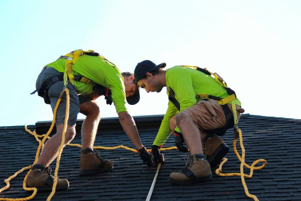 Two solar installers working on a shingle roof