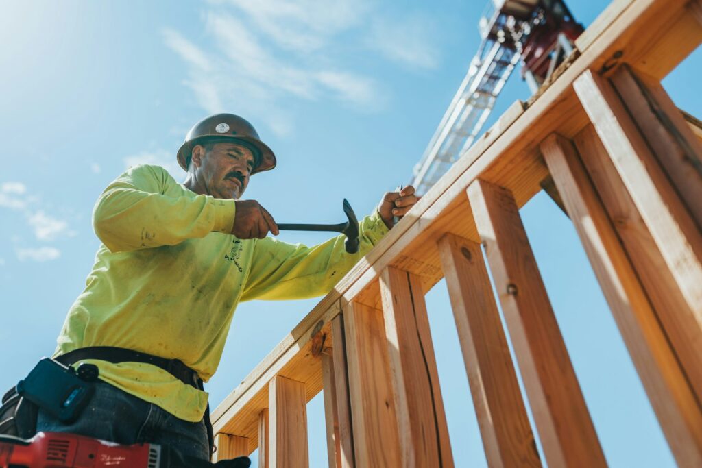 Carpenter hammering wood boards on a fence frame